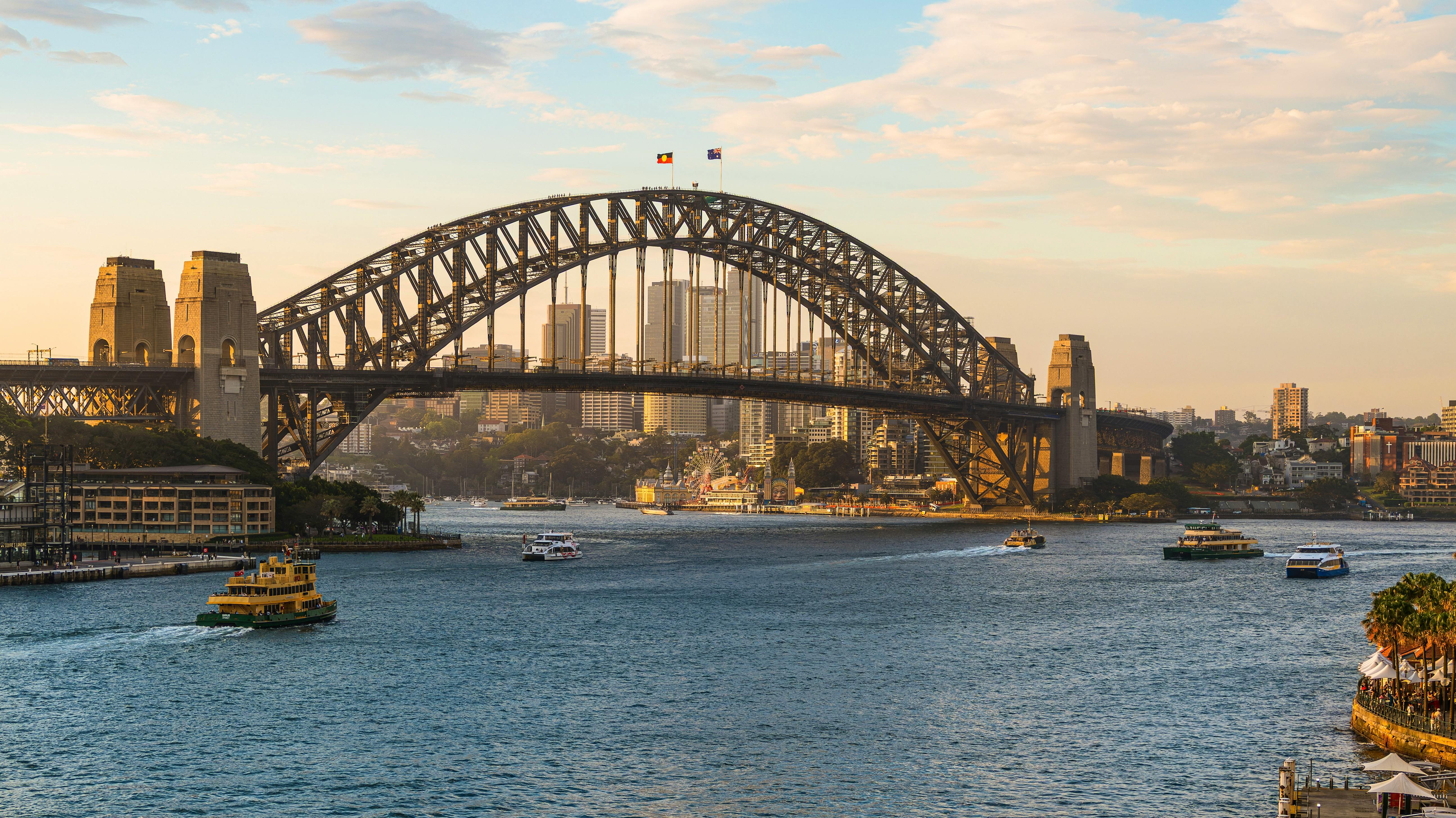 View of Sydney Harbour Bridge at sunset showing harbour waters and city skyline