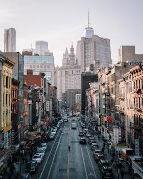 A bustling city street in New York City with people and cars under skyscrapers.