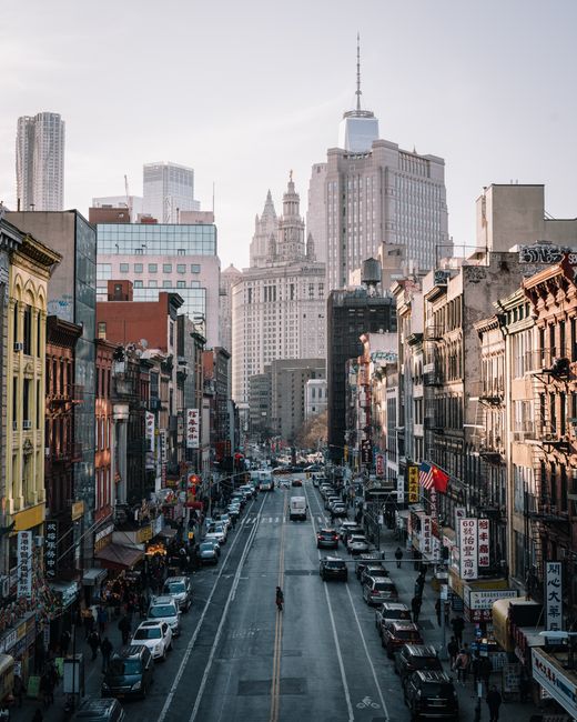 A bustling city street in New York City with people and cars under skyscrapers.
