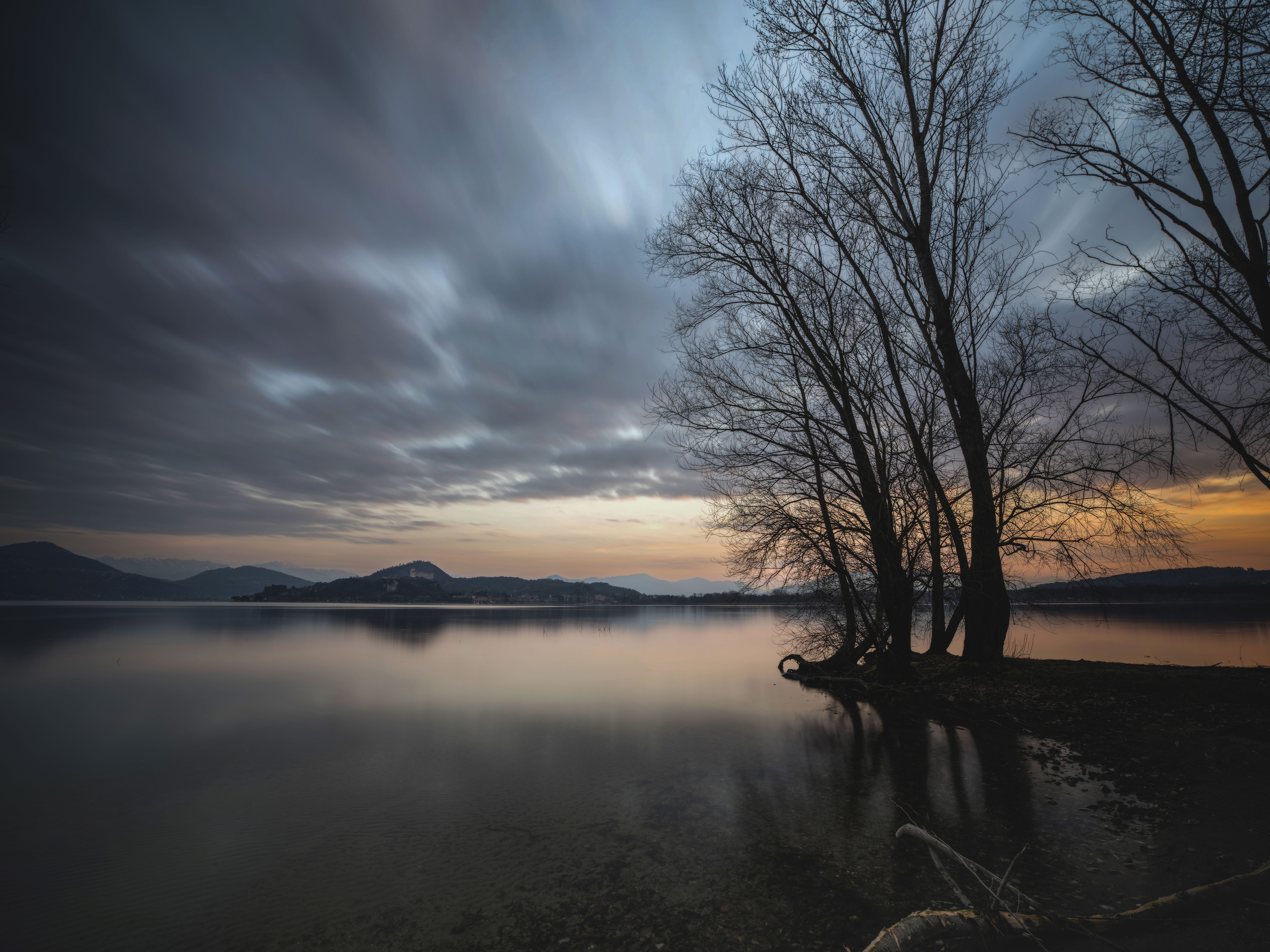 Serene Lakeside Sunset with Silhouetted Trees · Free Stock Photo