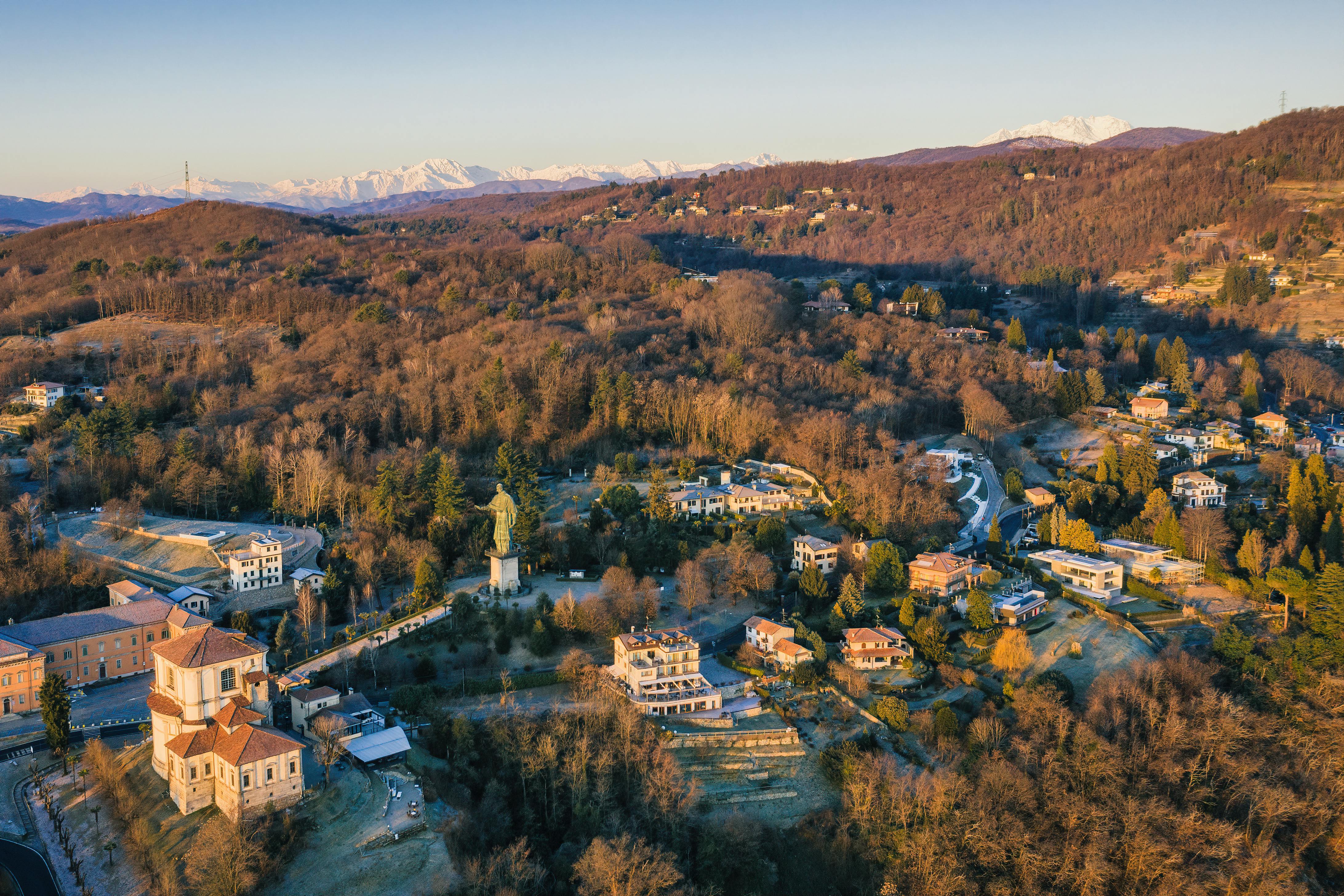 Scenic aerial view of Sacro Monte di Orta during winter, showcasing historical architecture and mountainous landscapes.
