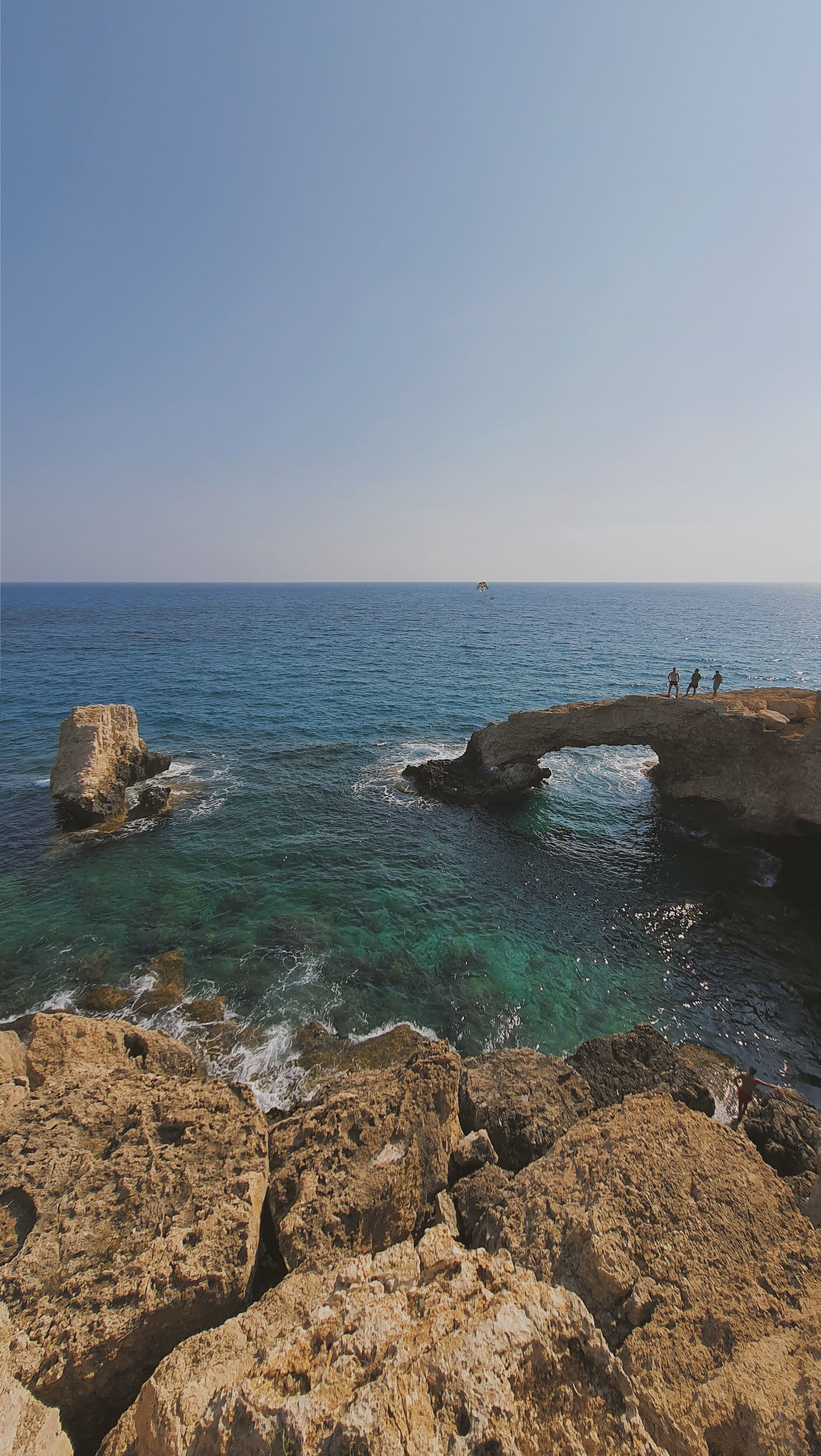 Stunning natural rock arch over the sea with clear blue skies in Cyprus, ideal for travel and nature themes.