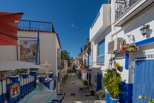 Free Picturesque narrow street in Alicante, Spain, with vibrant houses and clear blue skies. Stock Photo