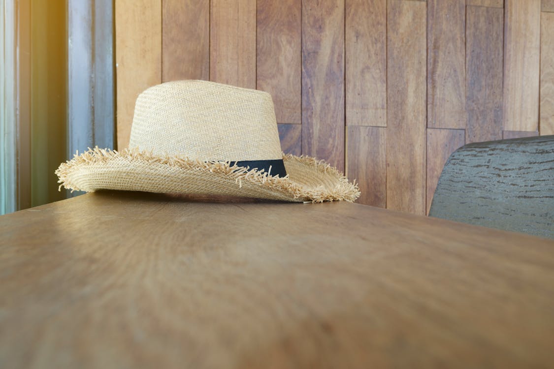 無料 木製の表面にベージュと黒の麦わら帽子 写真素材
