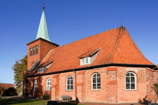 Beautiful red brick church with a green steeple in Drage, Niedersachsen, Germany captured in bright daylight.