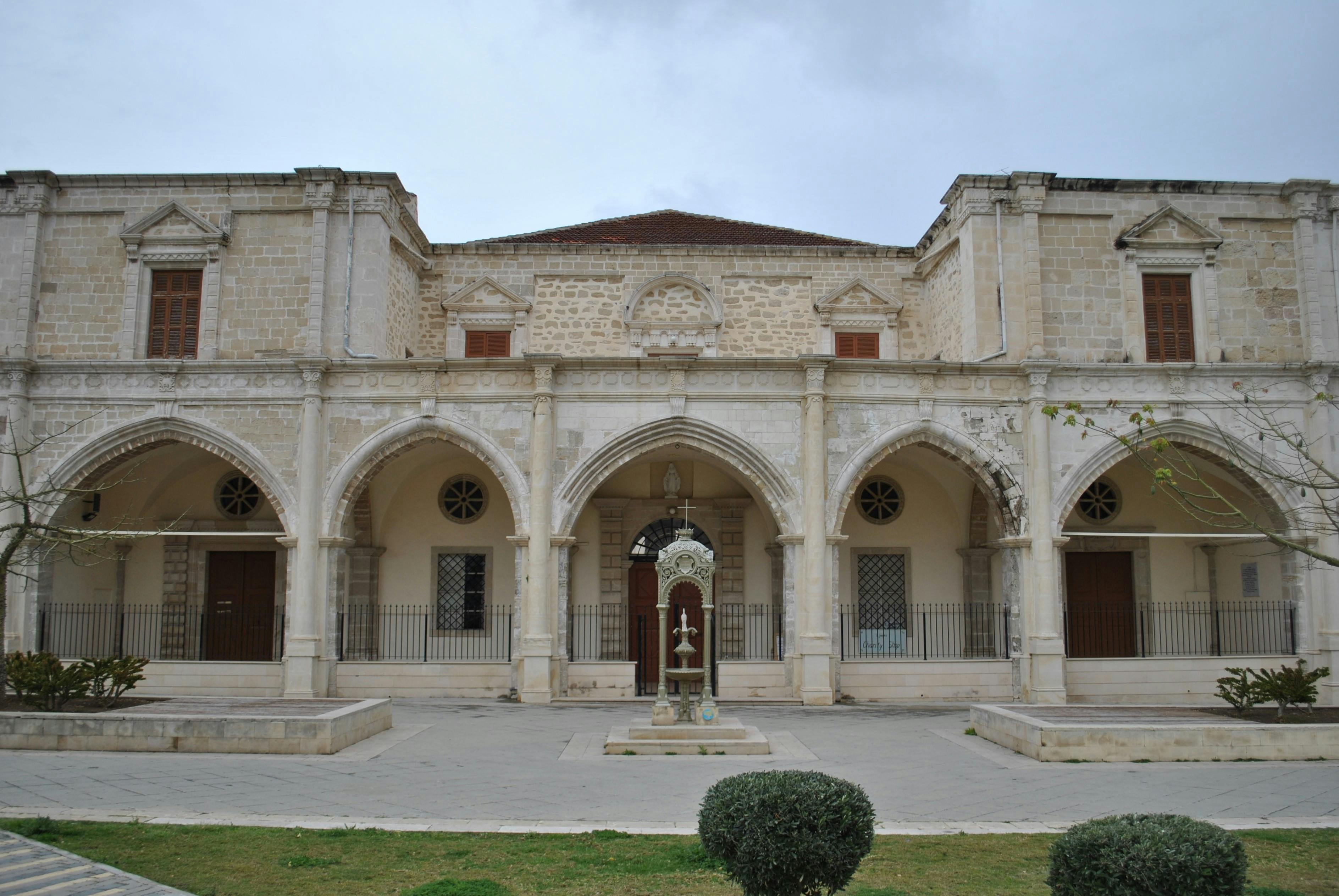 Elegant stone building with arched facade and central courtyard fountain.