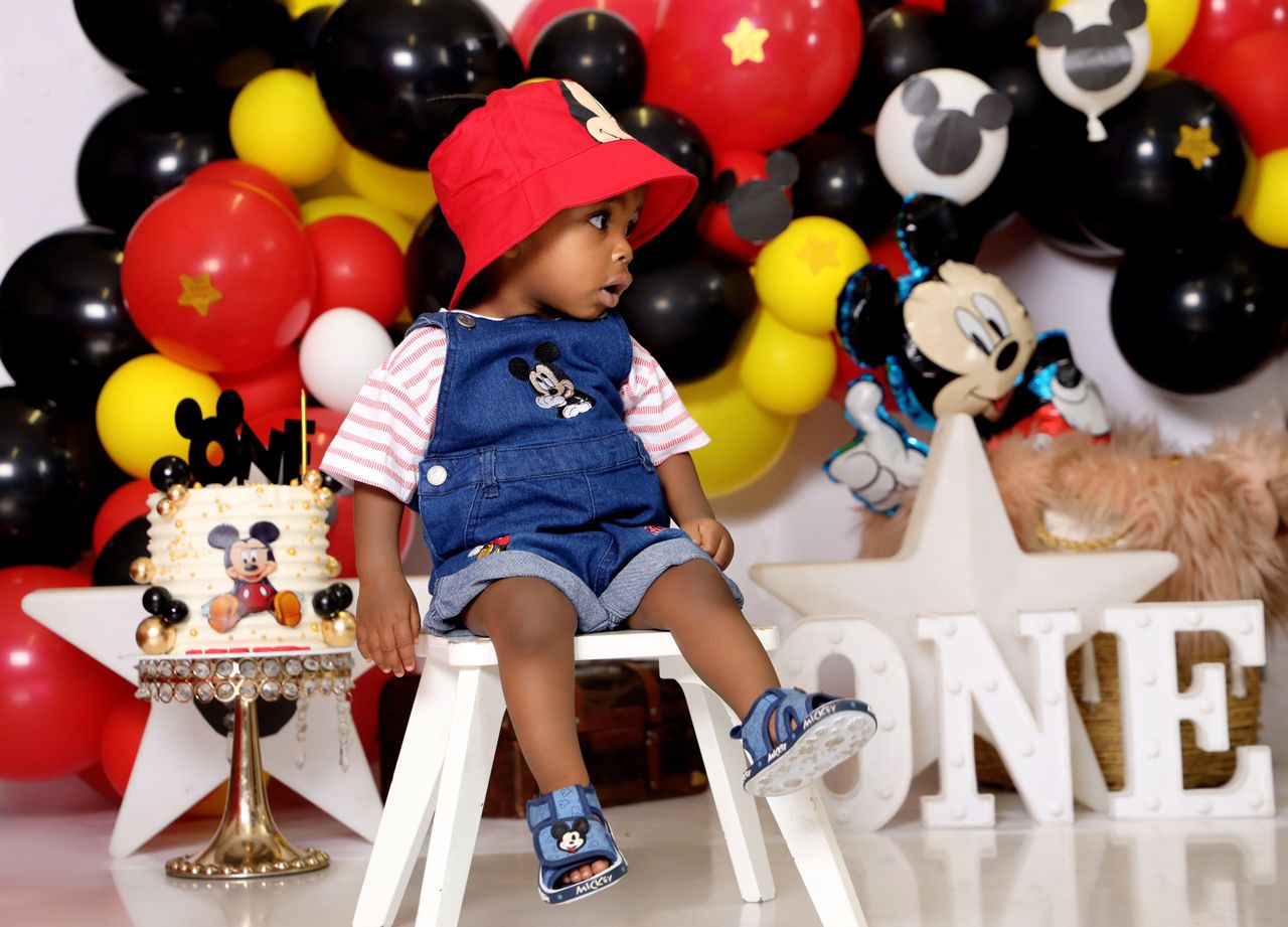 adorable baby in a mickey themed party setting celebrates first birthd