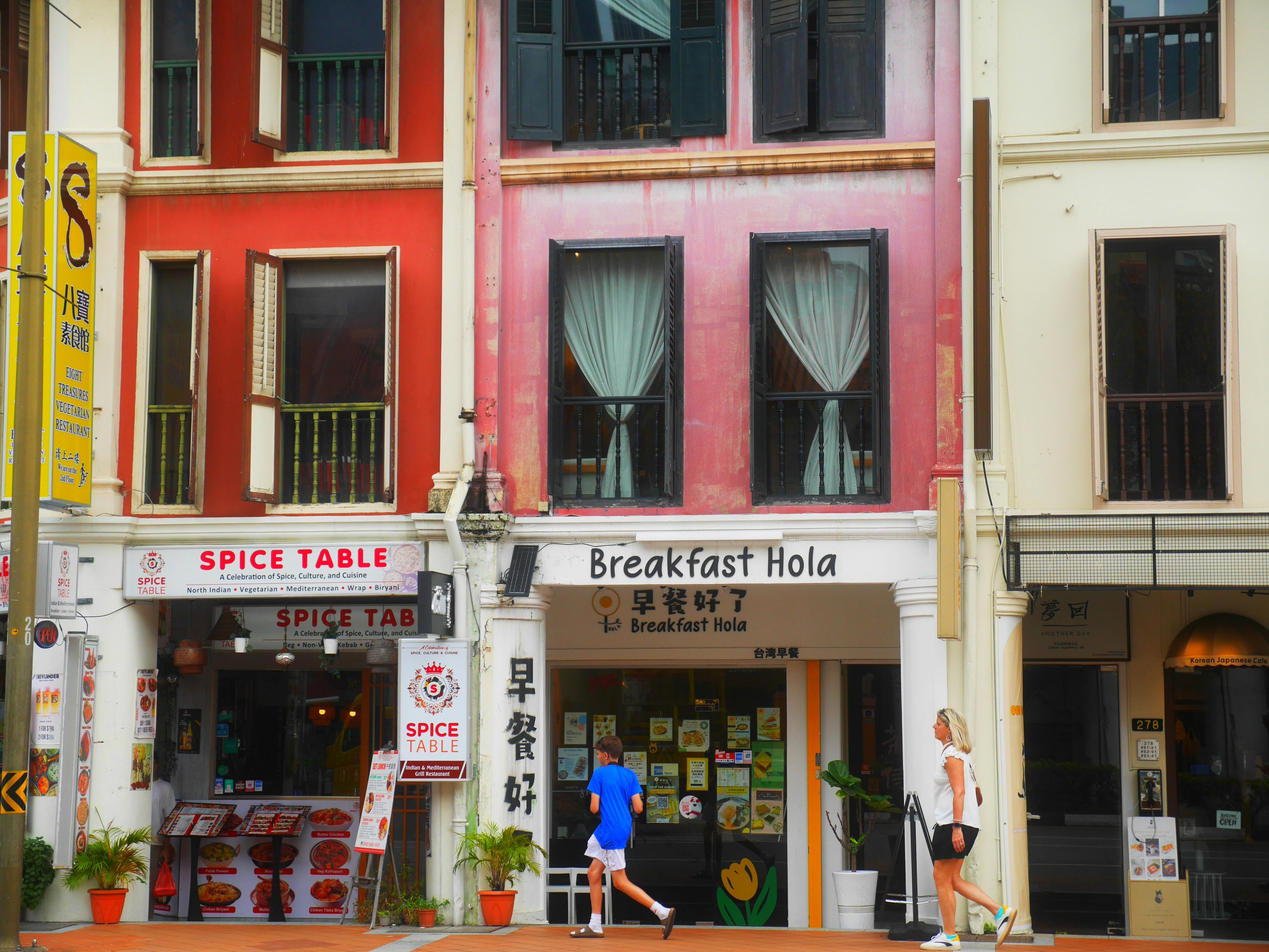 Vibrant city street with colorful buildings and shopfronts, lively urban atmosphere.