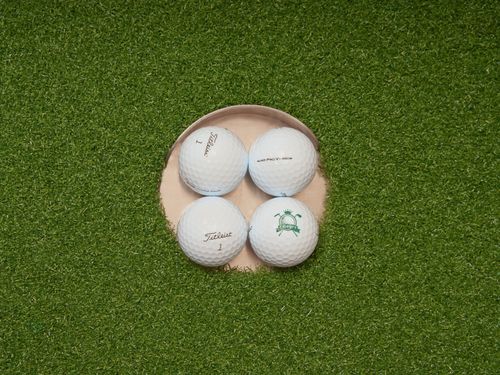 Free High-angle view of golf balls in a hole on an artificial turf putting green, ideal for golf practice visuals. Stock Photo