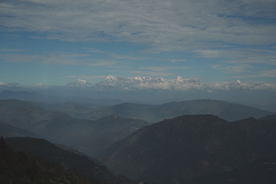 A breathtaking view of the Himalayan mountain range under a partly cloudy sky.