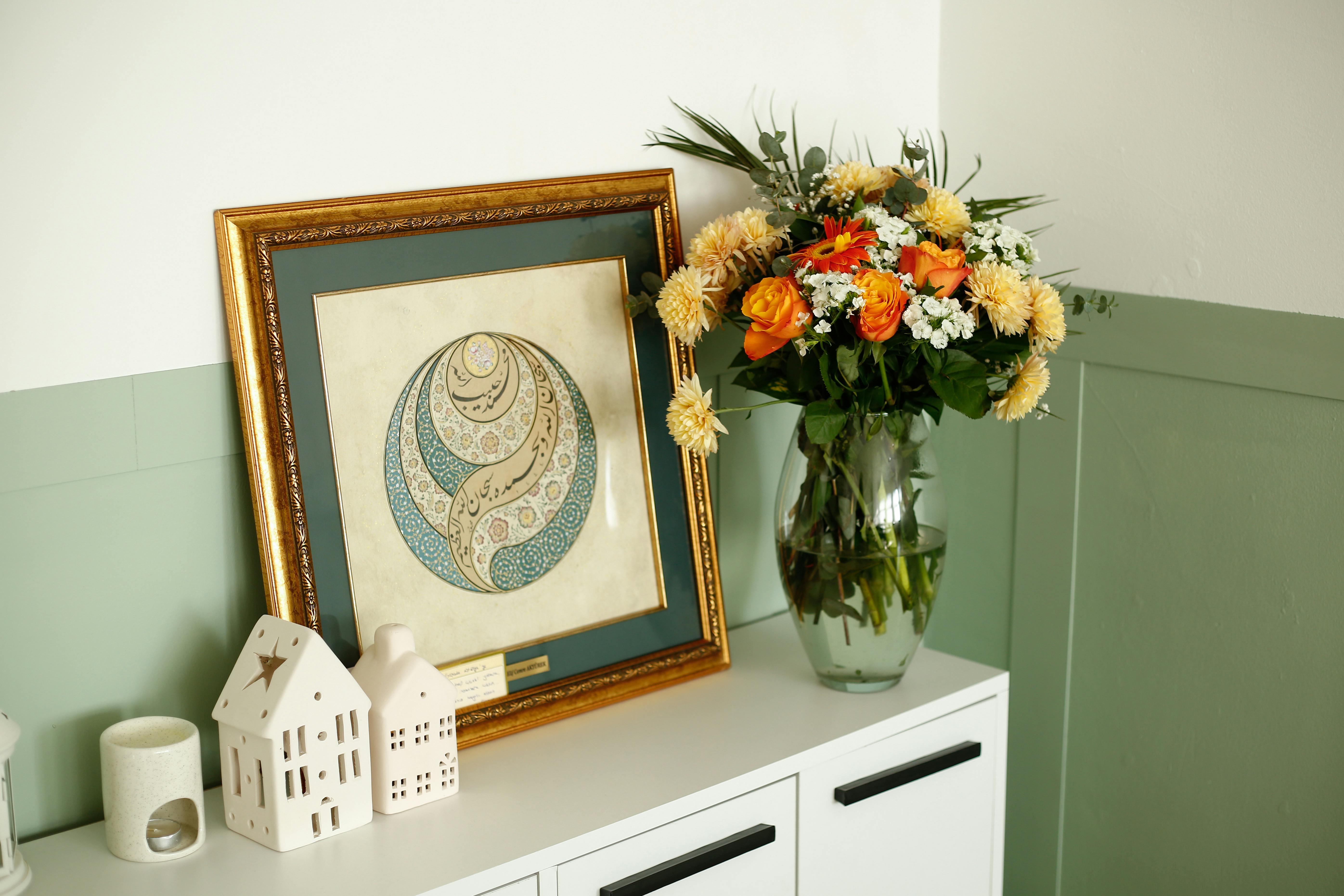 A stylish interior with a framed artwork and a bouquet of flowers, creating a warm atmosphere.