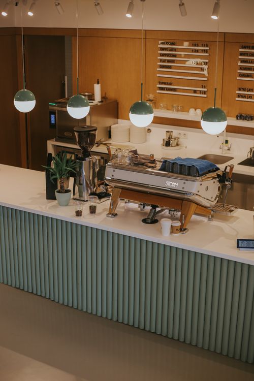 Free Chic coffee shop interior featuring a sleek espresso machine and modern green accents. Stock Photo