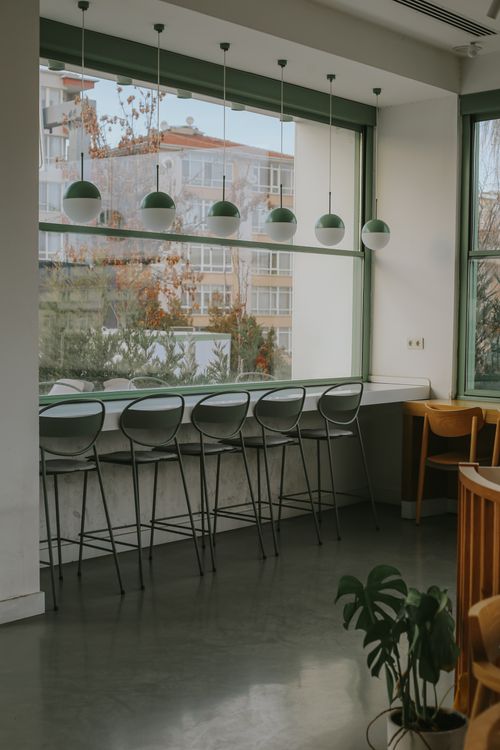 Free Modern cafe interior featuring high stools and pendant lights with large windows overlooking a pleasant view. Stock Photo