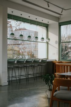 A serene and cozy cafe interior featuring green decor and natural light streaming through large windows.