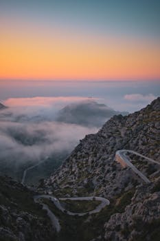 Winding road on Mallorca's mountains at sunset with breathtaking clouds and sky.