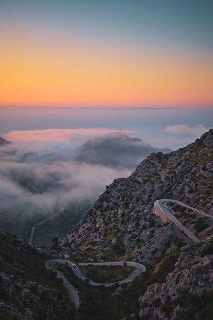 Winding road on Mallorca's mountains at sunset with breathtaking clouds and sky.