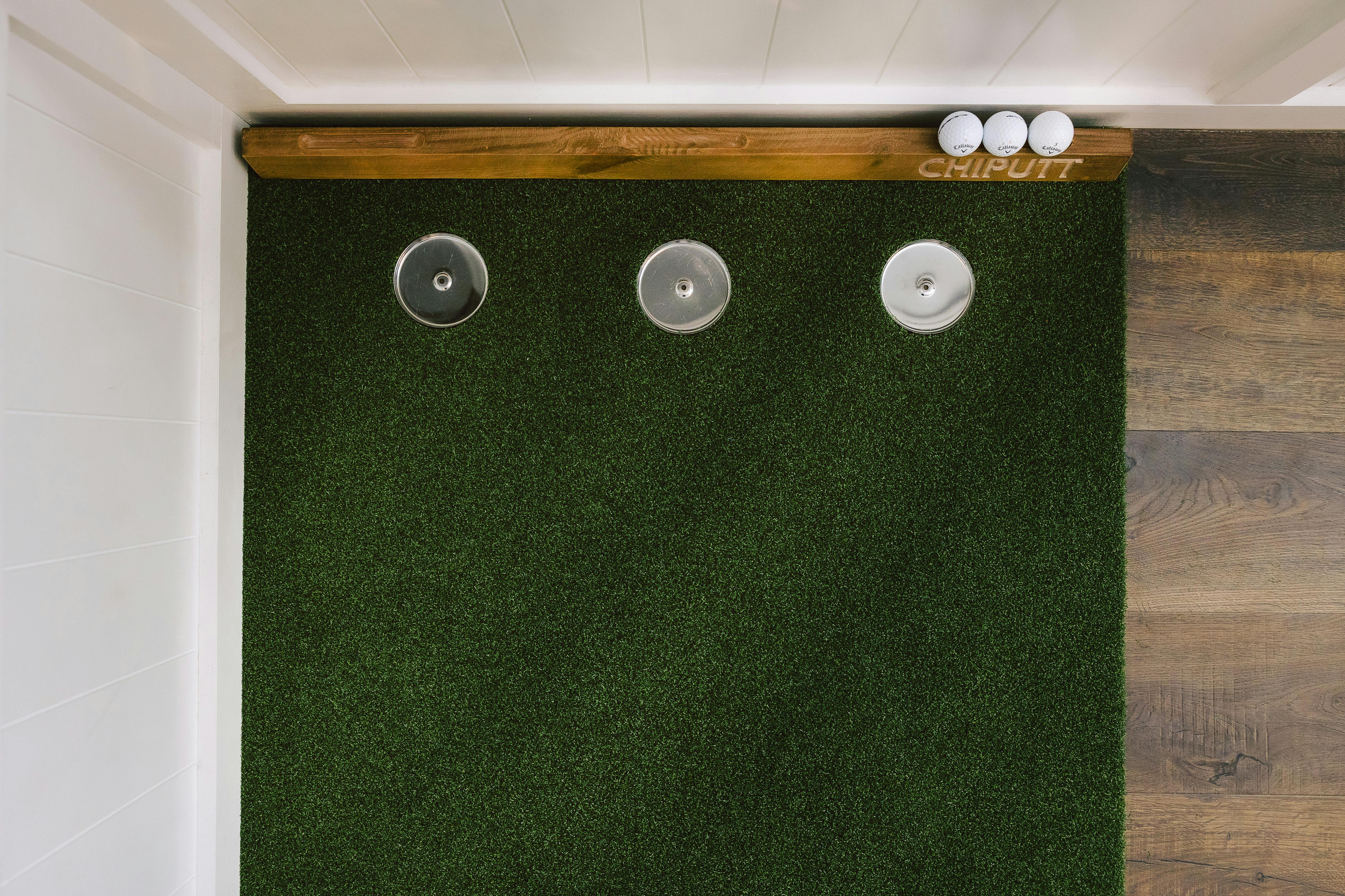 Top view of an indoor golf putting mat with golf balls and holes for practice.