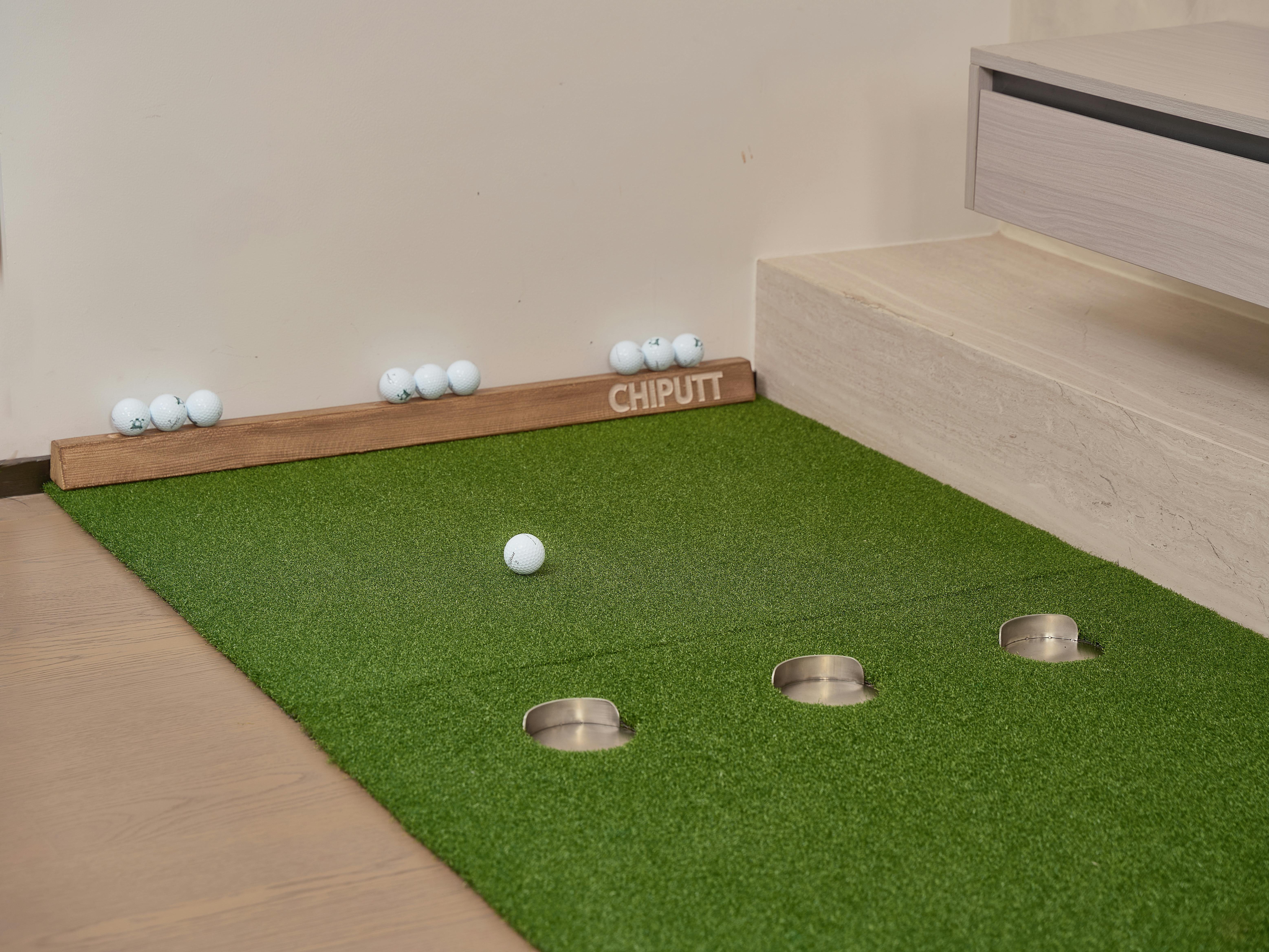 Indoor putting green with golf balls and equipment for golf practice at home.