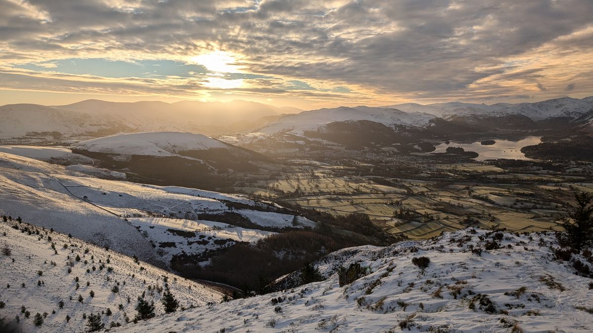 Snow-covered fells at sunrise looking down over Derwentwater.