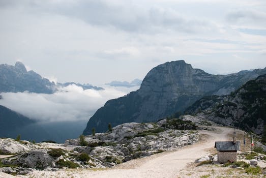 Dramatic mountain landscape with a rocky path in the Dolomites under a cloudy sky.