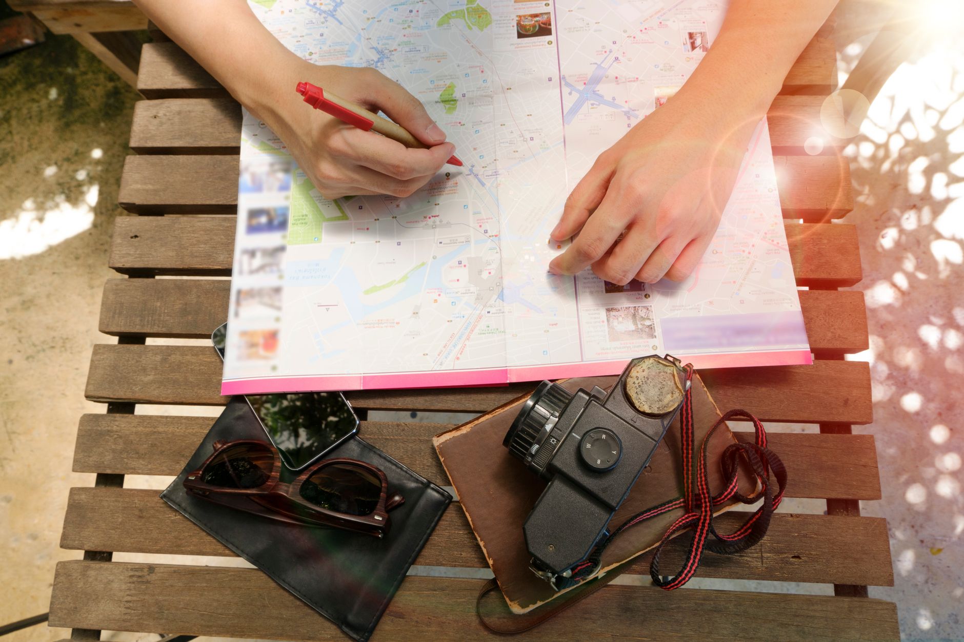 高雄文青景點推薦:老屋、書店、小店散步路線攻略 A person planning a journey using a map and vintage camera, evoking travel and exploration.
