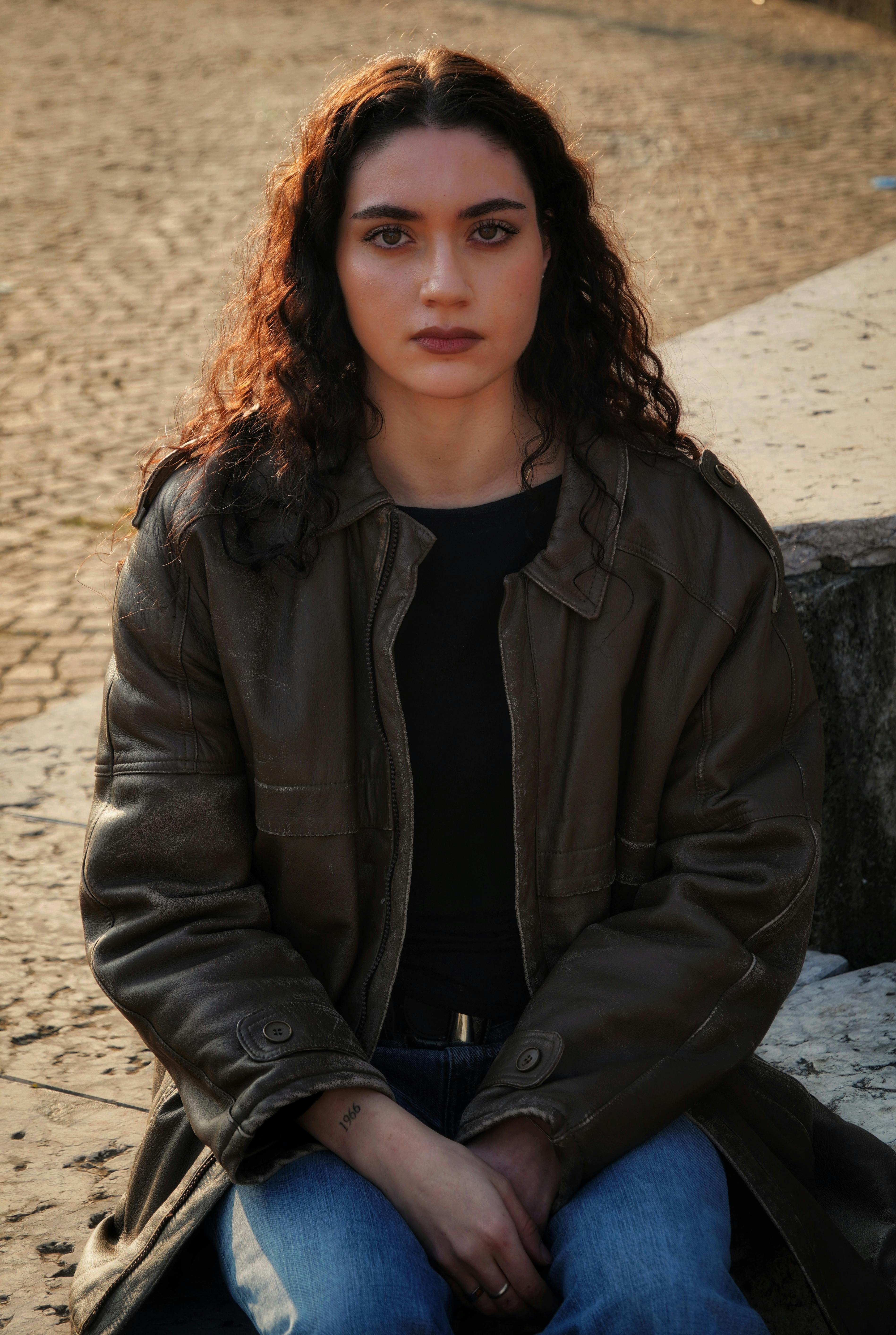 Portrait of a woman sitting outdoors in casual clothing, exuding confidence.