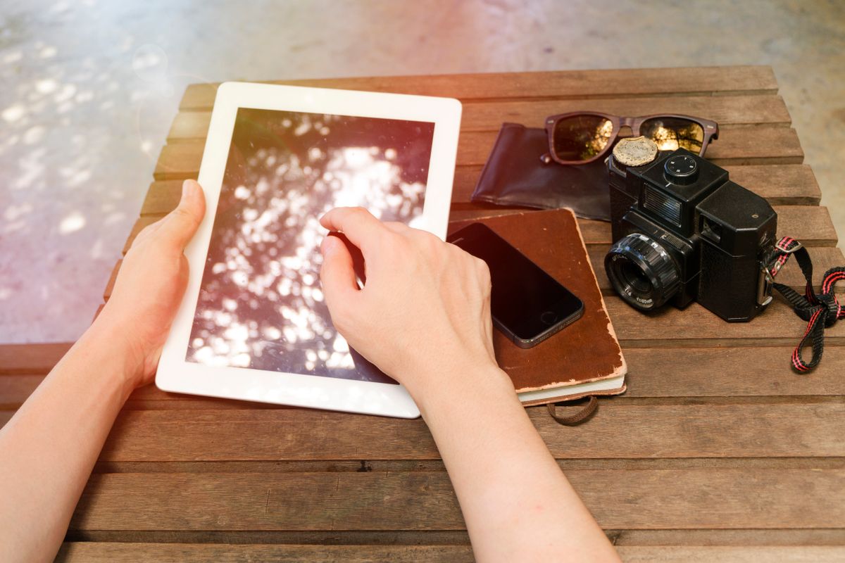 Masanın üzerinde açık bir tablet ve yanında altın madeni taşları, açık hava maden ortamı