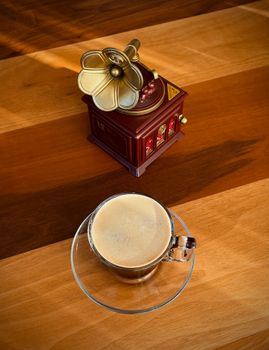 Cozy scene with a vintage gramophone and coffee cup on a wooden table, evoking nostalgia and tranquility.