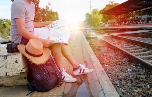 Man Sitting Beside Black Backpack Near Railway