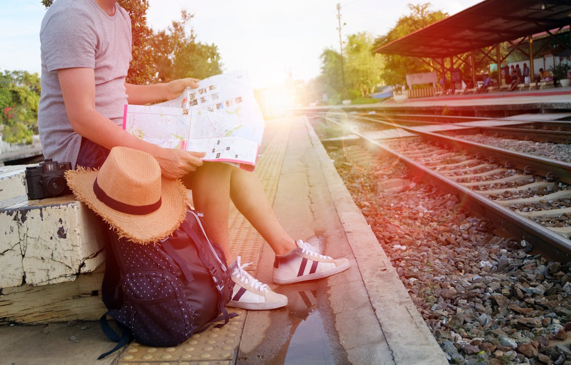 Man Sitting Beside Black Backpack Near Railway