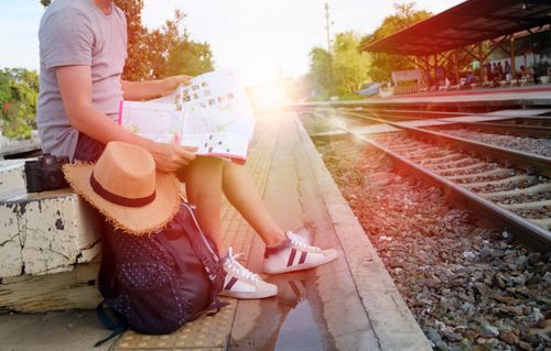 Traveller at train station platform reading a map before departure.