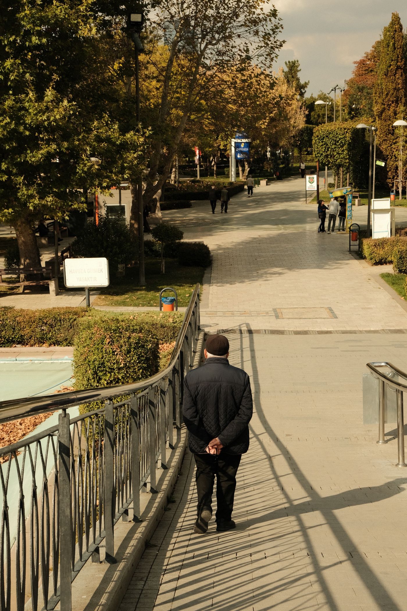 A person walking alone on a sunlit park pathway, representing gentle movement as a healthier way to cope with depression