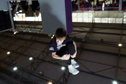 Free A young man performs a parkour flip indoors, showcasing athletic skills and agility. Stock Photo