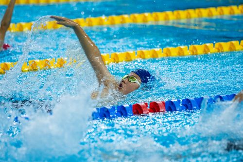 Free A competitive swimmer performing a backstroke in a race, creating splashes. Stock Photo