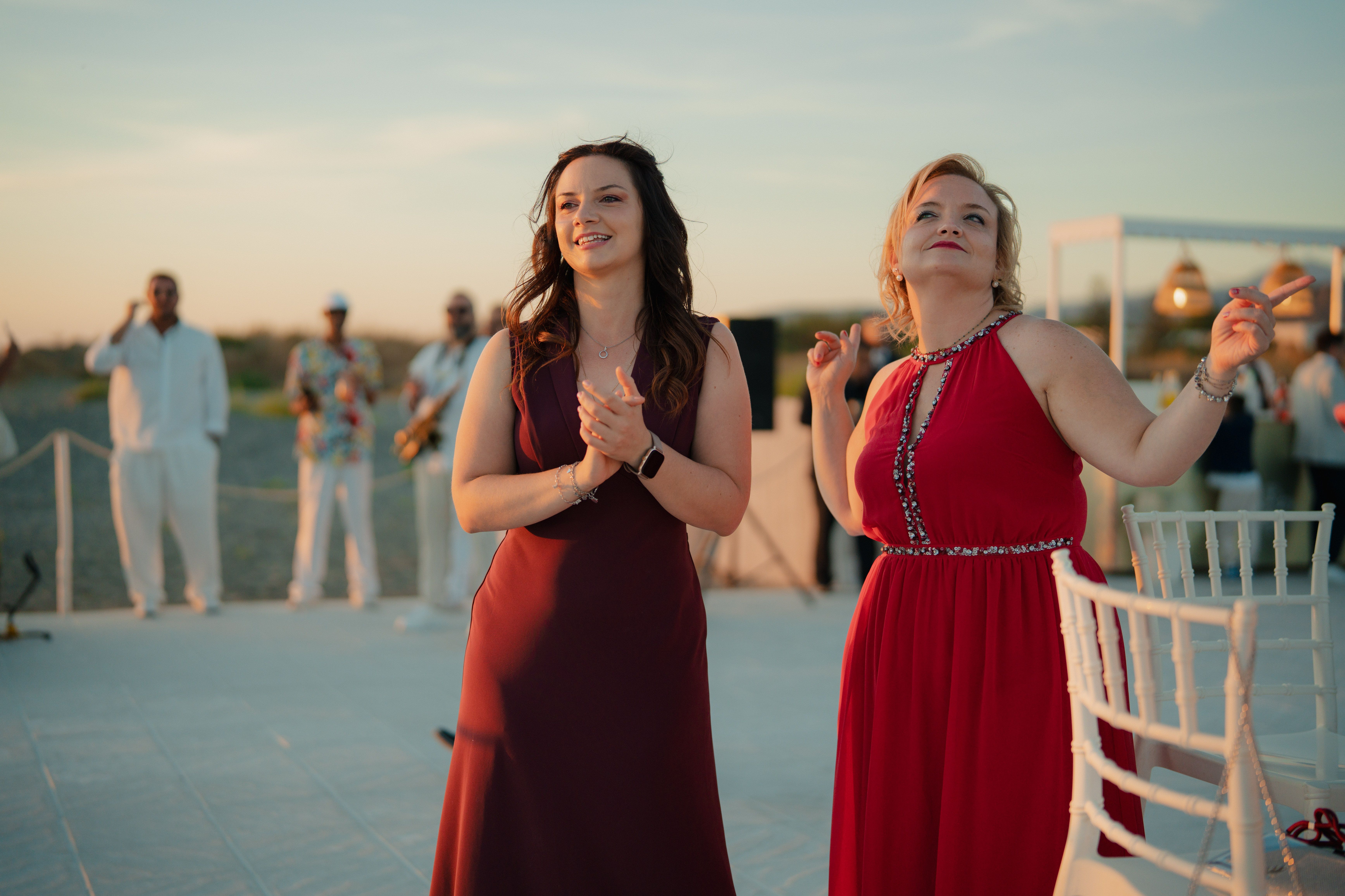 marassi summer event planner — Two women enjoying an elegant outdoor evening party with live music.