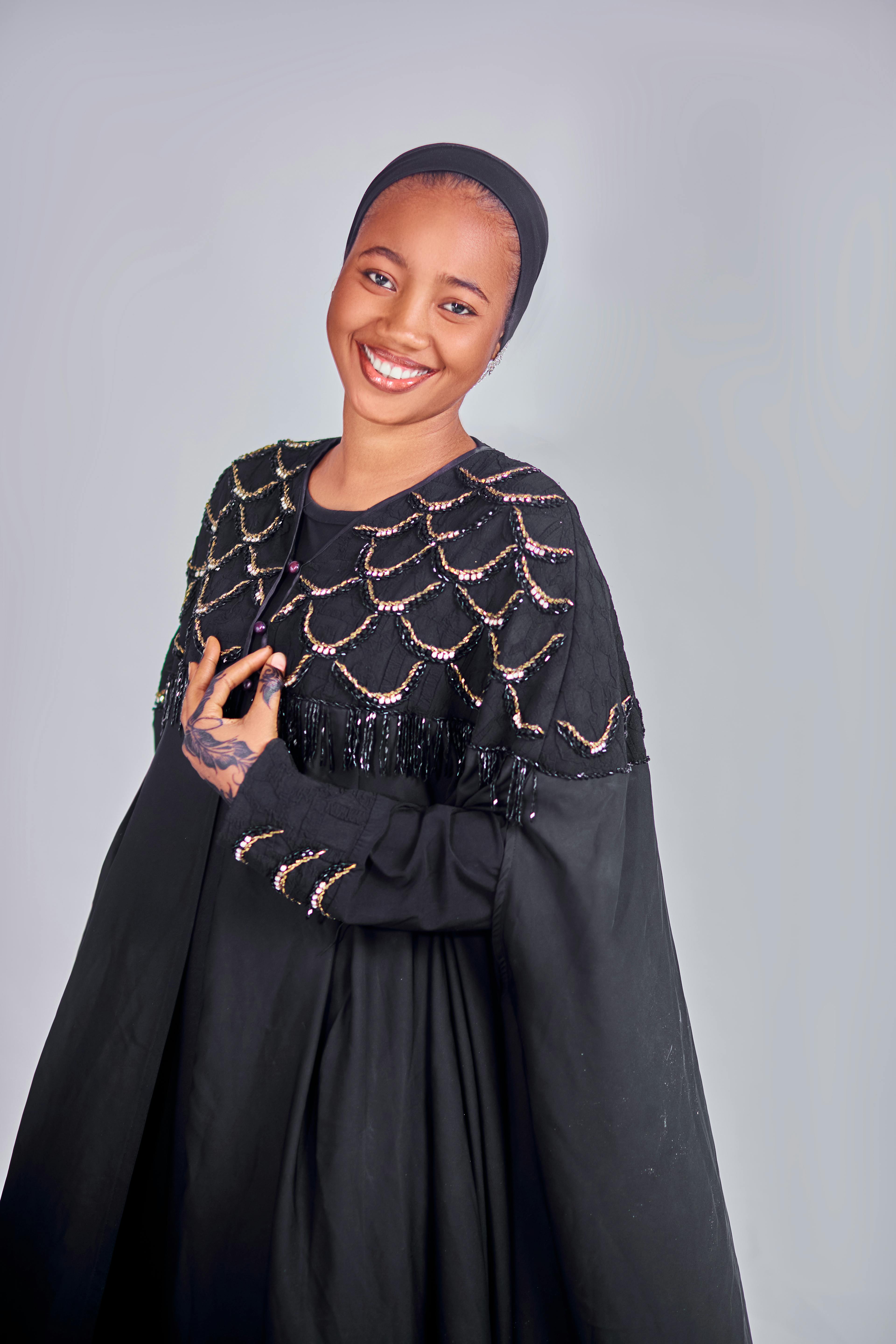 Woman in a black detailed dress with a joyful smile.