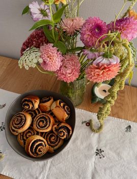 Colorful flowers and cinnamon rolls create a cozy autumn setting.
