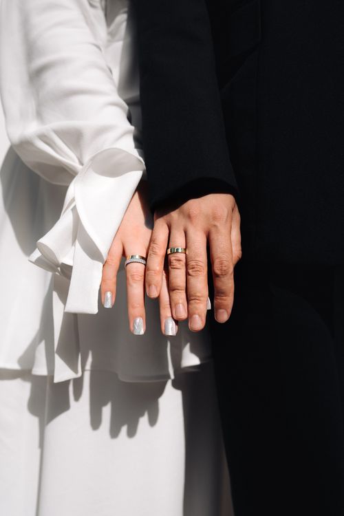 Free Close-up image of a couple holding hands, showcasing wedding rings and attire, perfect for wedding themes. Stock Photo