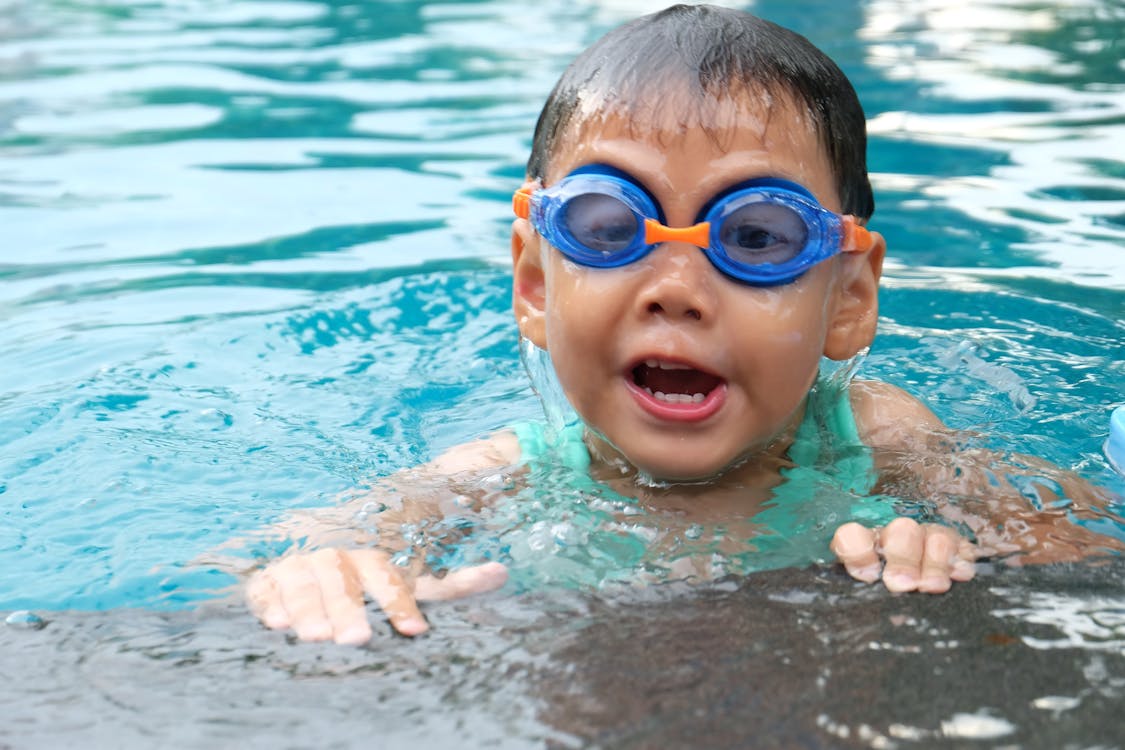 бесплатная Малыш плавает в бассейне в голубых очках Стоковое фото