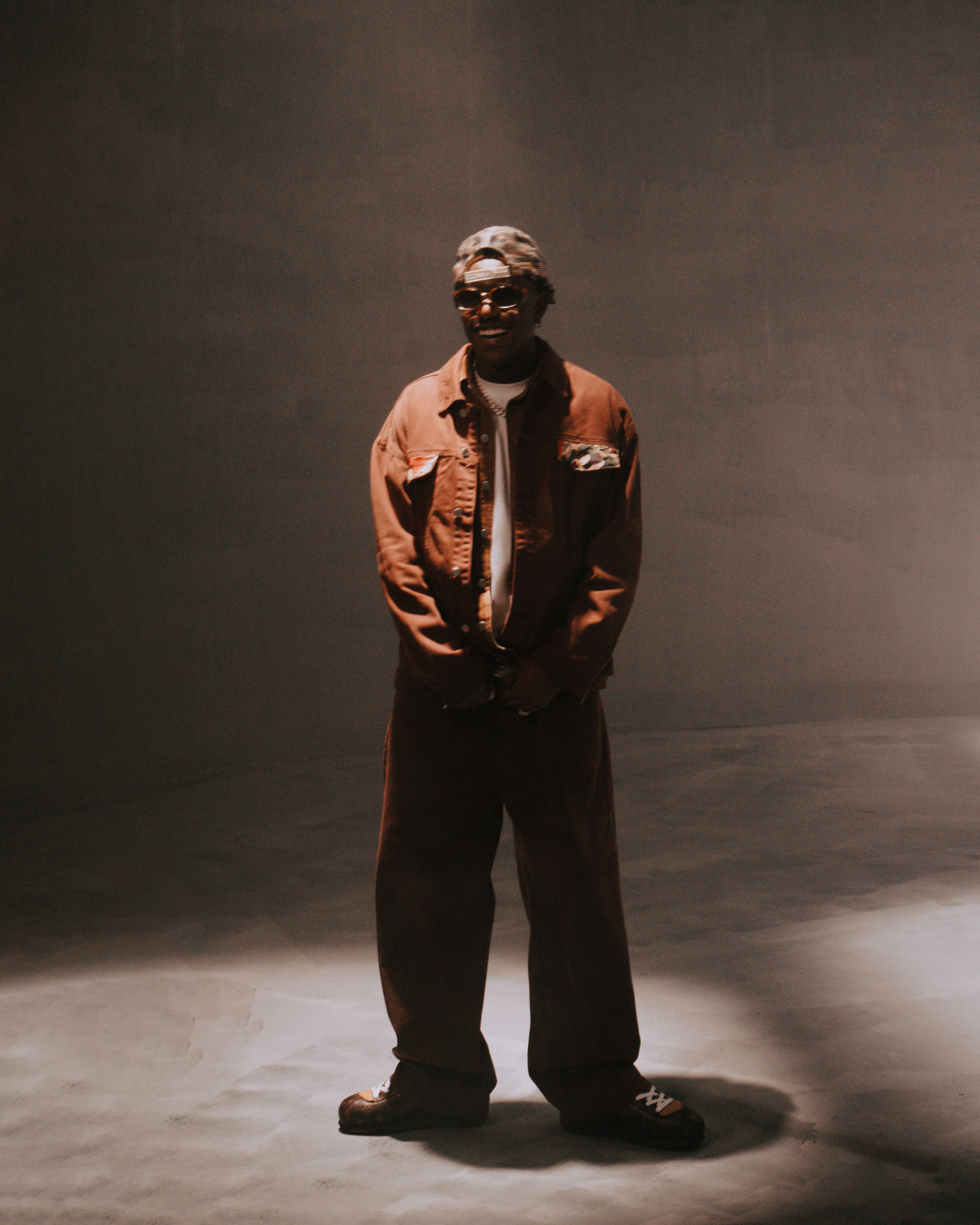 Artistic portrait of a stylish man in a dimly lit studio with vintage tones.