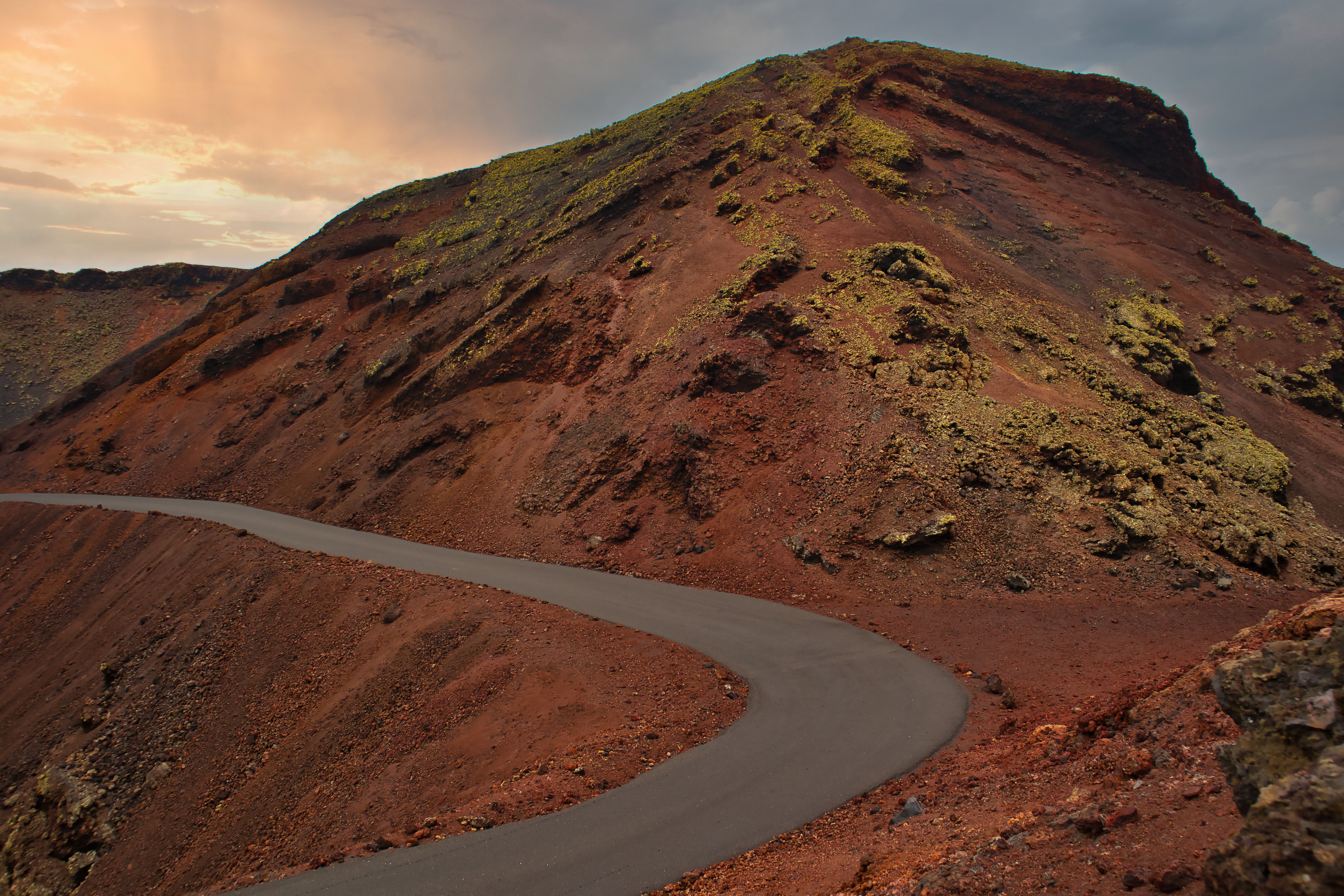 Curved road through a striking volcanic landscape in Lanzarote, showcasing unique terrain.