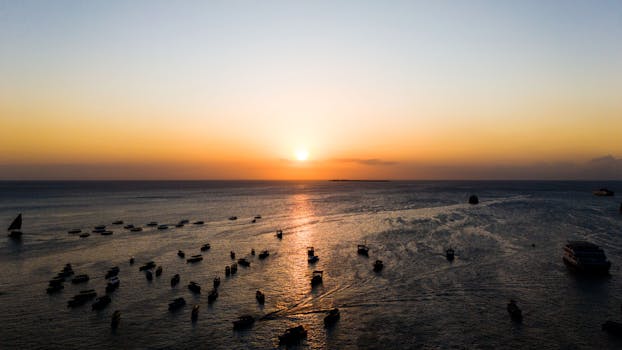Serene sunset view with boats in the waters of Stone Town, Zanzibar.