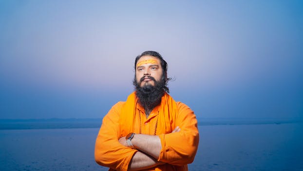 A spiritual Hindu Sadhu in orange attire stands by the Ganges River in Varanasi, India.