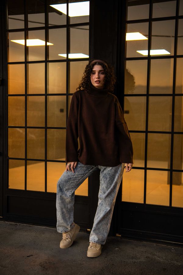 Woman in a cognac crewneck with dark-wash jeans and heels