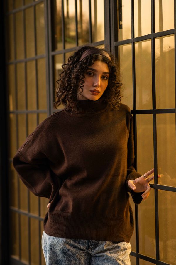 Woman in a brown cable-knit sweater with light-wash jeans and white sneakers