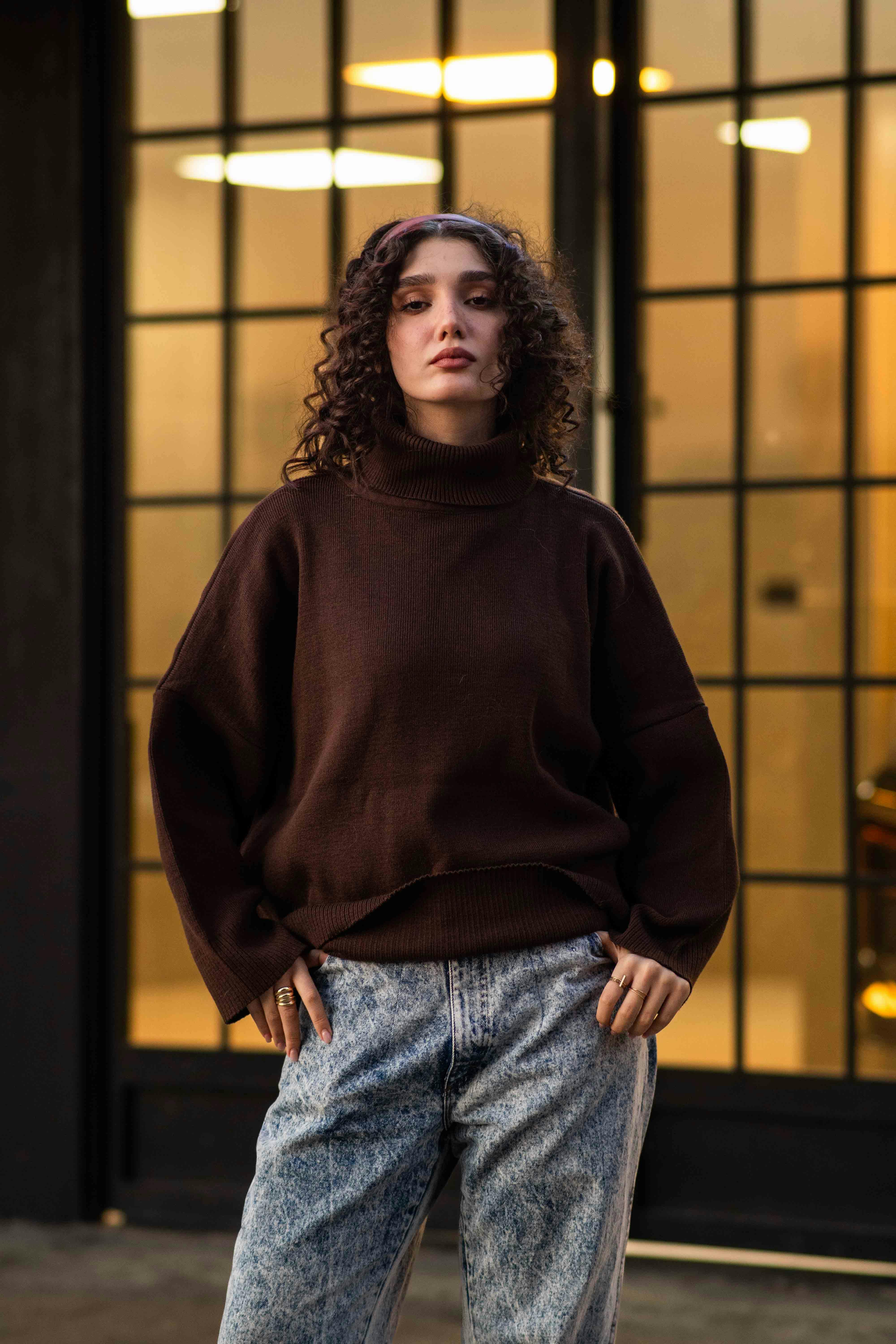 Stylish woman standing confidently in cityscape backdrop.
