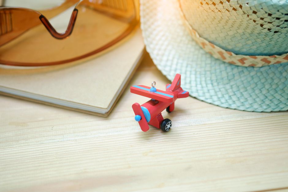 Flat lay of sunglasses, straw hat, and toy airplane symbolizing summer travel and adventure.