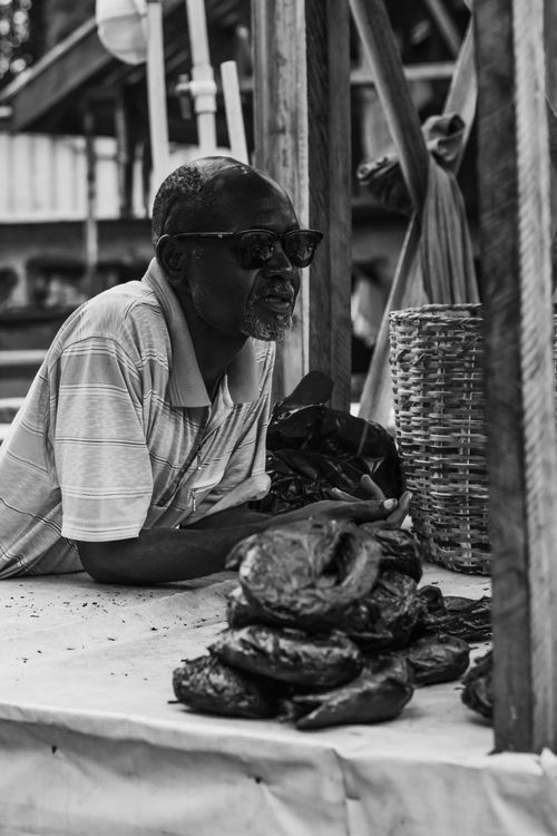 Free Elderly vendor selling goods at outdoor market; a glimpse of local culture. Stock Photo