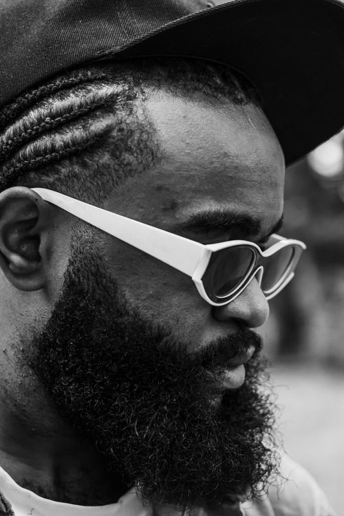 Free Close-up black and white profile of a man wearing sunglasses and a cap, showcasing style. Stock Photo