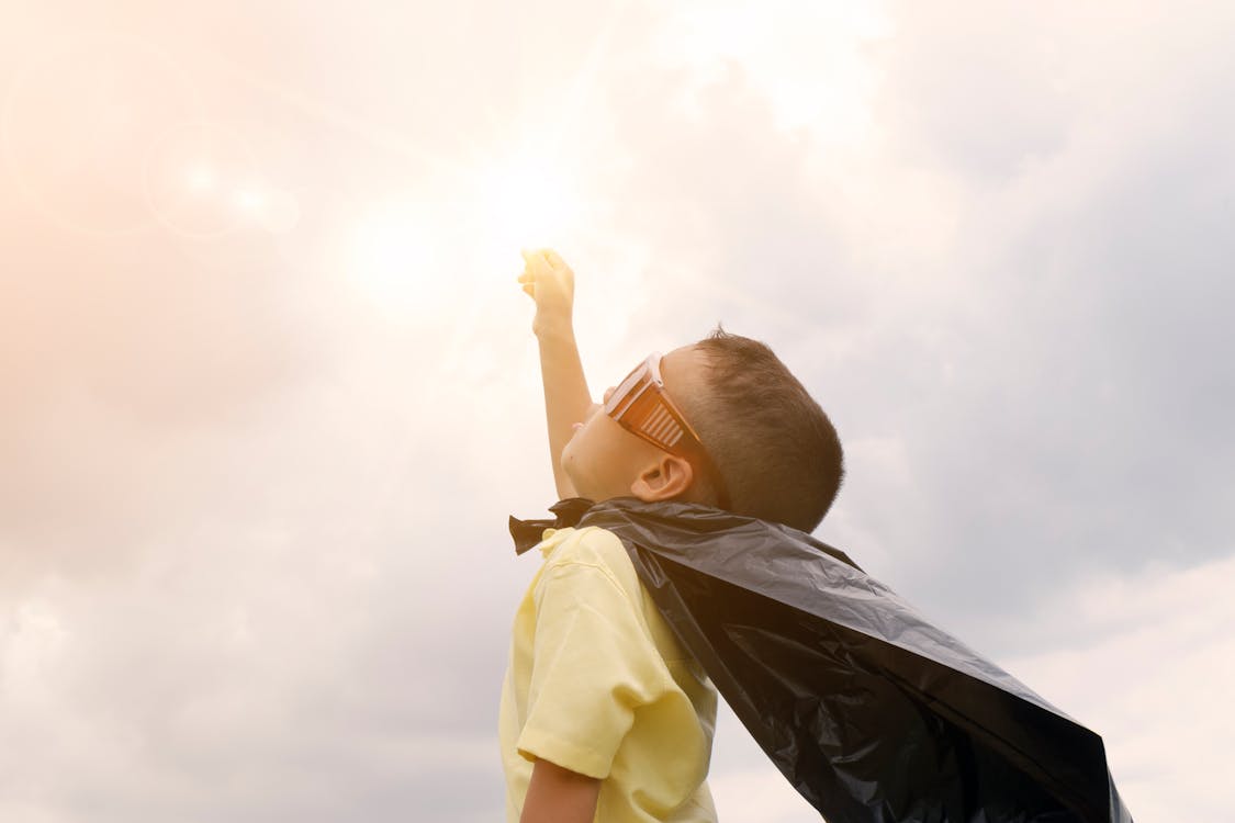 Boy Rising Up His Hand Wearing Black Cape